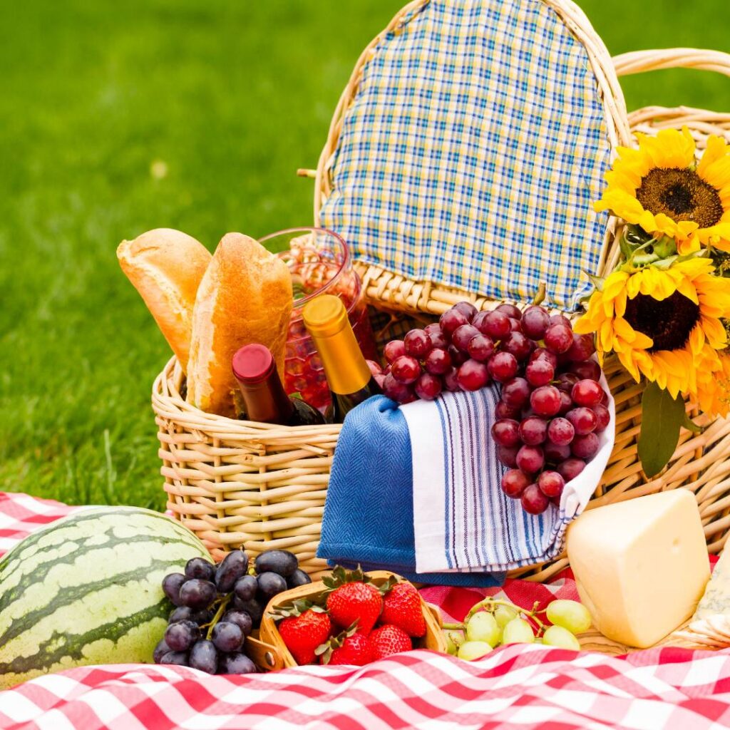 A picnic basket packed with tasty picnic treats on a red checked blanket