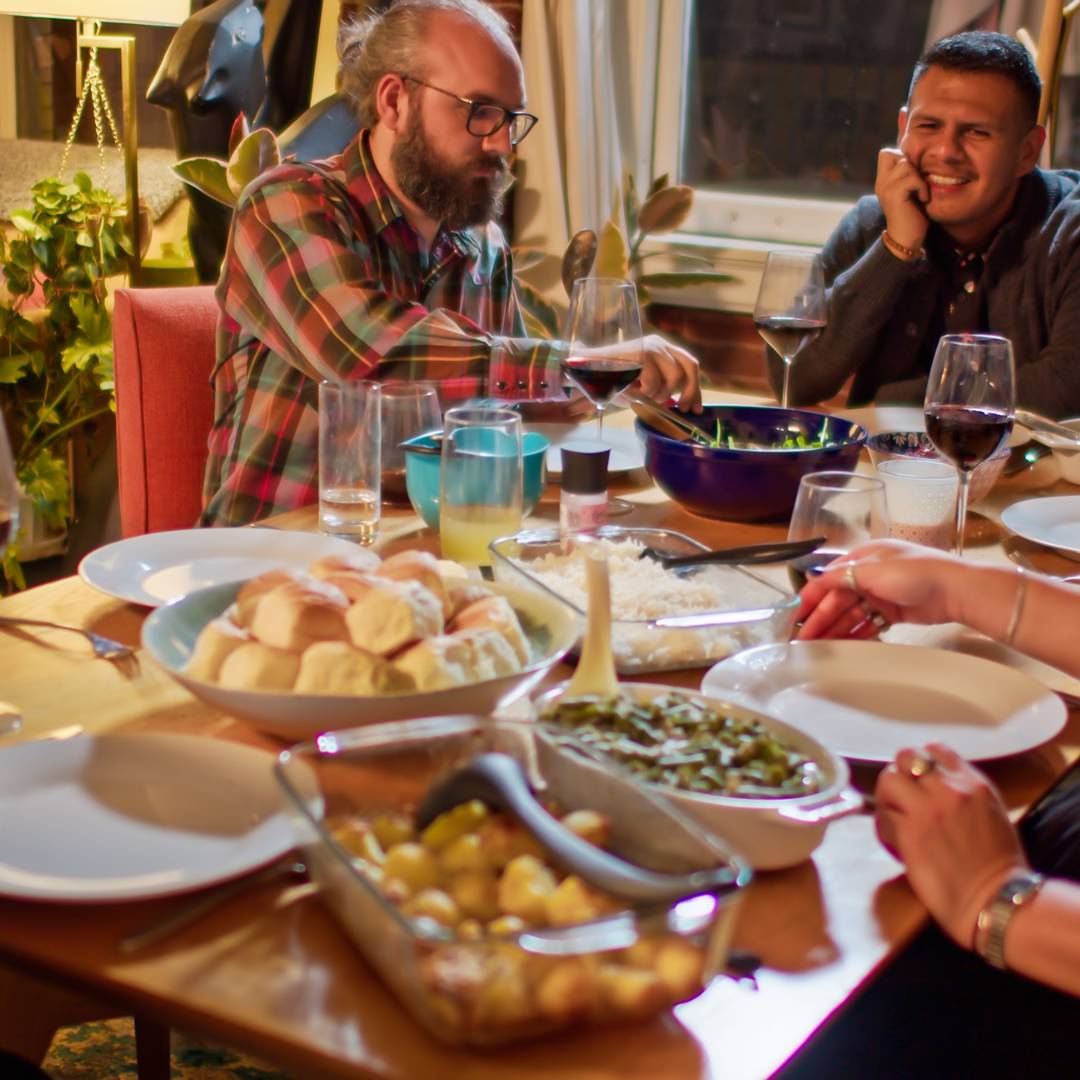 Friends gathered at the table enjoying a friendsgiving spread