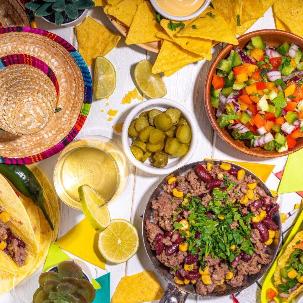 Fresh pico de gallo, taco meat, jalapeño, taco shells and tortilla chips spead out on a table