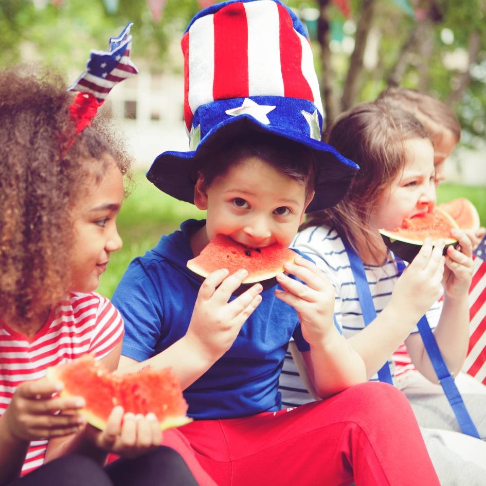 Little boy with American Flag hat eating watermelon happily