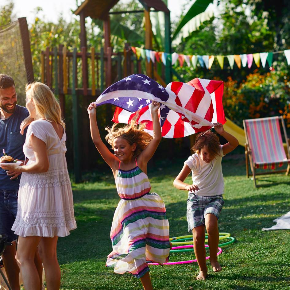 Kids running in the yard under an American Flag